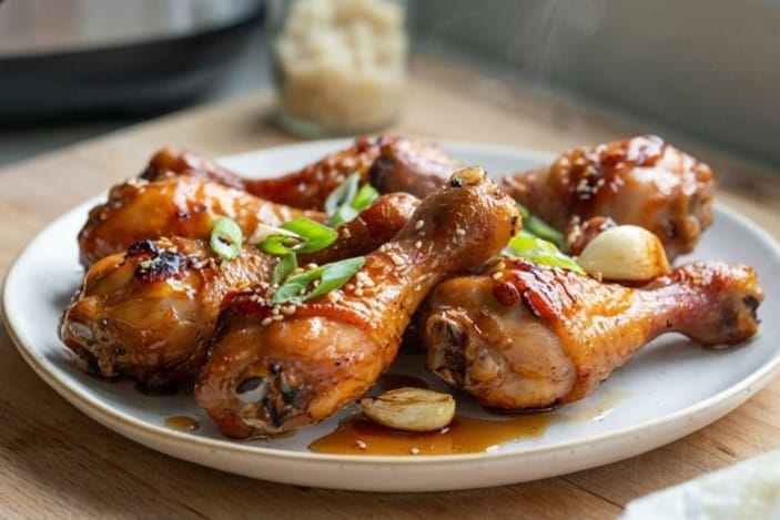 Honey Garlic Air Fryer Chicken Drumsticks That Actually Crisps 9 Honey Garlic Air Fryer Chicken Drumsticks arranged on a white plate with sticky glaze and crispy golden-brown skin