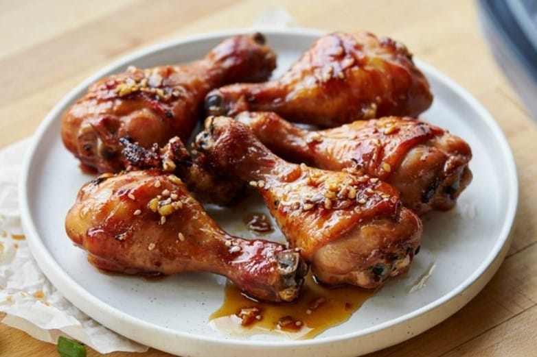 Honey Garlic Air Fryer Chicken Drumsticks That Actually Crisps 11 Honey Garlic Air Fryer Chicken Drumsticks with crispy golden skin coated in a sticky honey garlic glaze on a serving platter